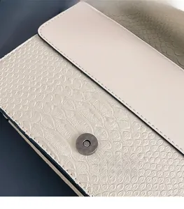 Close-up of premium faux snakeskin texture and magnetic metal clasp on ivory crossbody bag