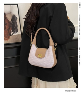 Detail of contrast stitching and gold twist lock on stylish crescent shoulder bag