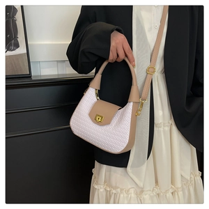 Detail of white woven texture and khaki trim on a lady handbag with gold clasp