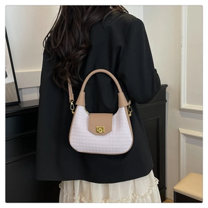 Close-up of white woven crescent bag with gold rotary lock and adjustable leather strap