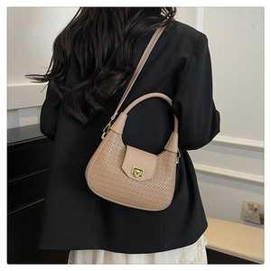 Detail of woven crescent bag featuring a gold square twist lock and smooth leather trim