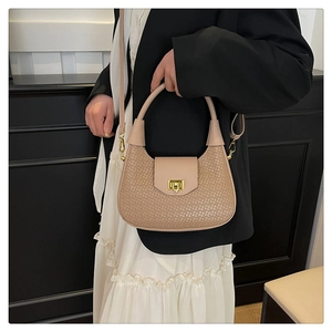 Detail of beige woven half-moon crossbody bag with gold lock on a female model