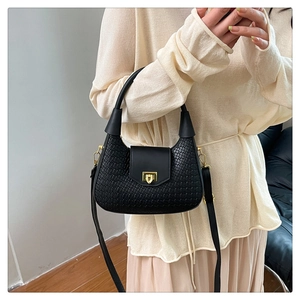 Detail of black woven crescent bag with gold twist lock and adjustable shoulder strap