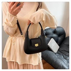 Detail of woven texture handbag with gold metal lock on casual crescent shoulder bag