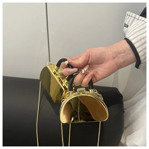 Detail einer goldenen Mini-Box-Tasche mit Spiegelglanz, Kettenriemen und Griff