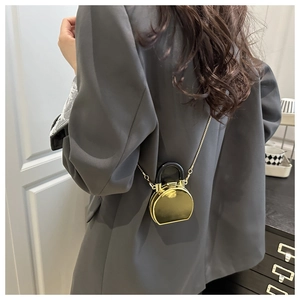 Moderne goldene Spiegel-Ministasche mit schwarzem Griff und Kette auf Blazer-Modell