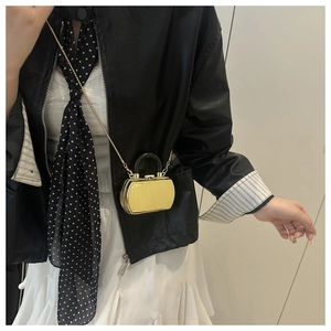 Detail der goldglänzenden Mini-Hardshell-Tasche mit Kettenriemen und schwarzem U-Griff