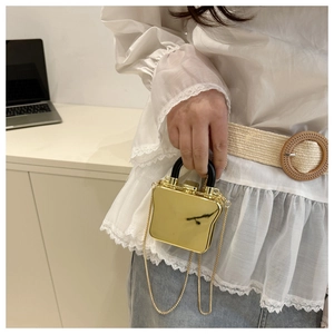 Detail einer mini goldener Spiegel-Tasche mit Kette und schwarzem U-förmigem Griff