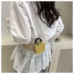 Mini goldene Kettentasche in Toastform als Taillen-Accessoire auf weißer Jeans