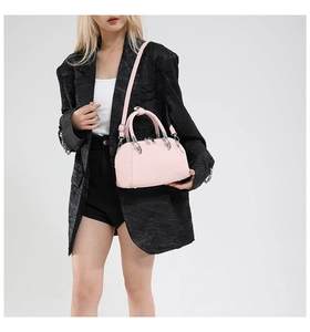 Detailed view of pink snake-pattern leather handbag worn with a black blazer