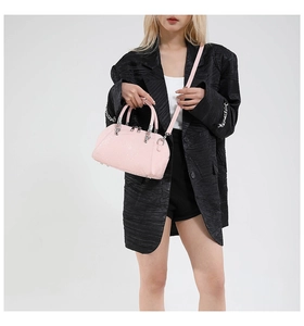 Pink boston bag with ostrich leather texture shown on model with adjustable strap