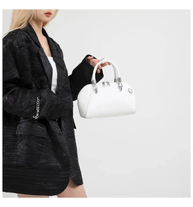 Detail of white snake-embossed shell handbag with silver hardware held by model