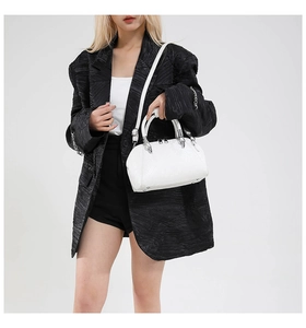 White snake pattern shell handbag shown with black blazer in a professional studio