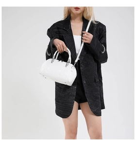 Detail view of white snakeskin texture shell bag with silver buckles and detachable strap