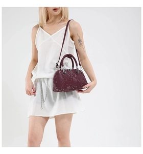 Detail shot of vintage snake pattern handbag in deep burgundy with silver metal hardware