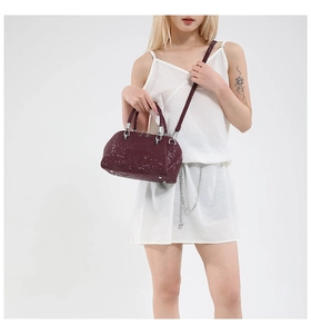 Detail of burgundy snakeskin shell bag with silver hardware and leather shoulder strap