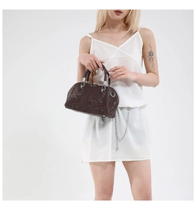 Detail of dark brown faux snakeskin texture on shell bag with silver metallic hardware