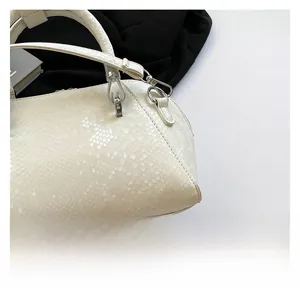 Close-up of white snakeskin texture and silver hardware on a luxury shell handbag