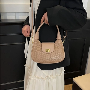 Elegant beige woven texture crossbody bag with gold hardware shown on a model
