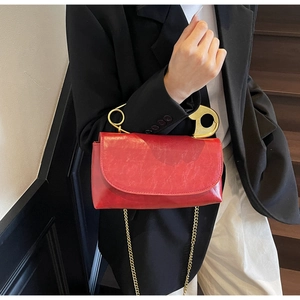 Vue détaillée du sac en cuir verni rouge avec poignée épingle dorée et bandoulière chaîne