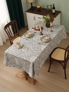 Close-up of grey linen tablecloth with white leaf patterns and smooth drape on a table