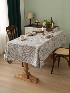 Close-up of thick linen tablecloth featuring elegant white leaf patterns on grey fabric