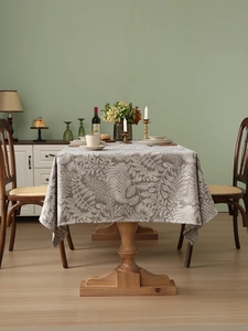 Detail of taupe rectangle tablecloth with white leaf pattern on a wooden table