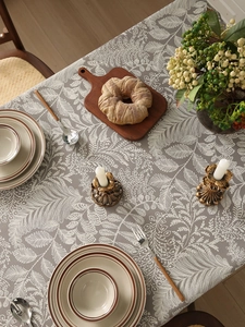 Close-up of grey linen tablecloth with white leaf pattern in a cozy dining setting