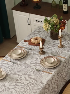 Detailed view of grey linen tablecloth with white leaf patterns and elegant table setting