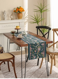 Detailed pattern of a dark teal floral table runner on a vintage wooden dining table
