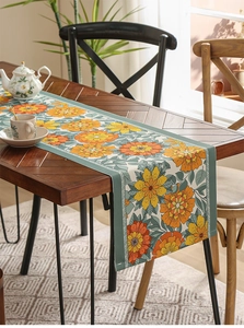 Detail of floral table runner with orange patterns on a rustic wooden dining table