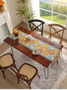 Close-up of floral table runner with orange daisies on a dark wood dining table