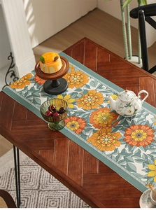 Detail of floral table runner with orange blossoms on a vintage green grey textured fabric