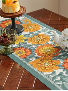 Close-up of vintage floral table runner with orange blossoms and duck egg green leaves