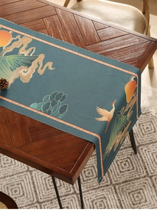 Close-up of crane and mountain patterns on teal waterproof table runner with orange border