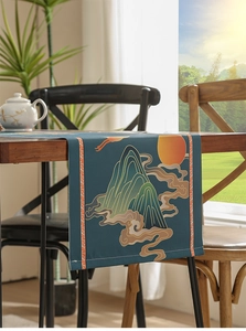 Close-up of a dark blue waterproof table runner with golden mountain and red sun patterns