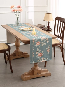 Detail of blue floral table runner with pink roses on wooden table in rustic setting