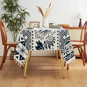 Detail of blue and white linen tablecloth featuring floral patterns and fringe edges