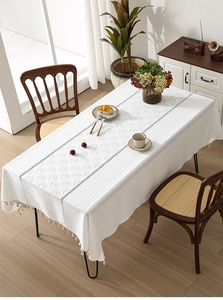 Close-up of white fabric tablecloth featuring circular jacquard texture and elegant tassel edges