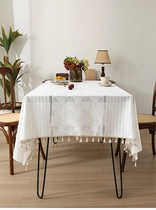 Close-up of elegant white French lace tablecloth featuring vintage tassels and floral texture