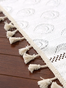Close-up of bohemian white lace tablecloth featuring elegant scalloped edges and tassels