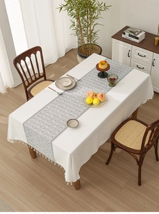 Detail of white waffle texture tablecloth and bohemian geometric table runner with tassels