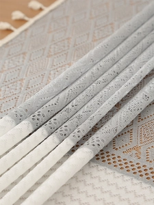 Macro detail of geometric lace tablecloth with grey and white patterns and fringe edges