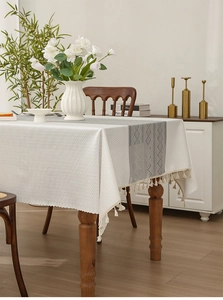 Close-up of cream textured tablecloth with grey diamond patterns and elegant fringe