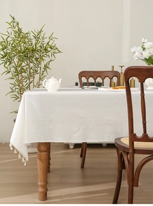 Close-up of beige woven tablecloth texture with fringe edge on a wooden table