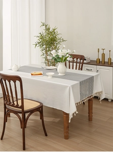 Detail of white herringbone tablecloth with grey diamond runner and tassel edges