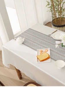 Detail of French jacquard lace tablecloth with geometric embroidery and tassel edges