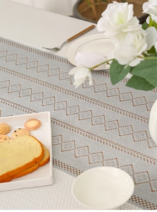 Detail showing grey geometric hollow lace table runner with intricate knit patterns