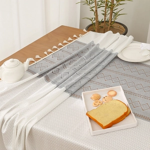 Nordic grey and white geometric hollow table runner with elegant tassels on wood table