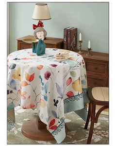Macro detail of a round cotton linen tablecloth with watercolor leaf patterns and lace edge